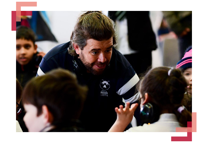 A picture of a man with a Bristol Bears jersey speaking to children