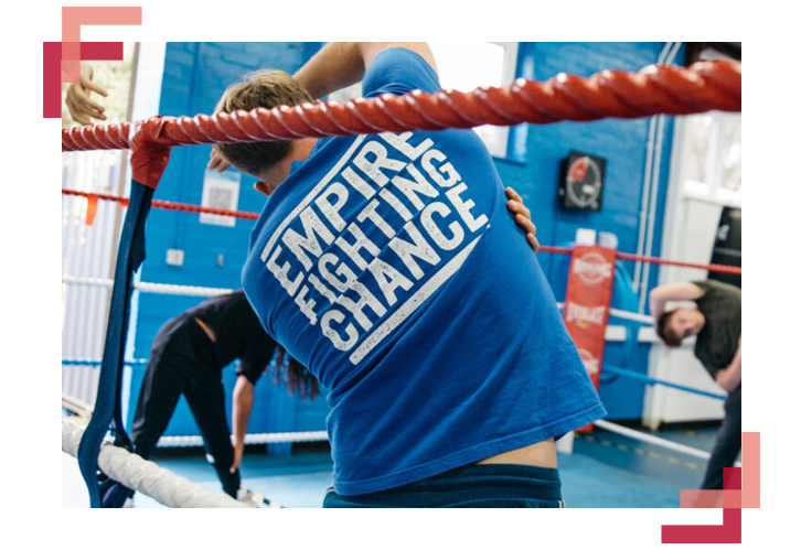 A picture of group of people warming up in a boxing ring with Empire Fighting Chance's t-shirts